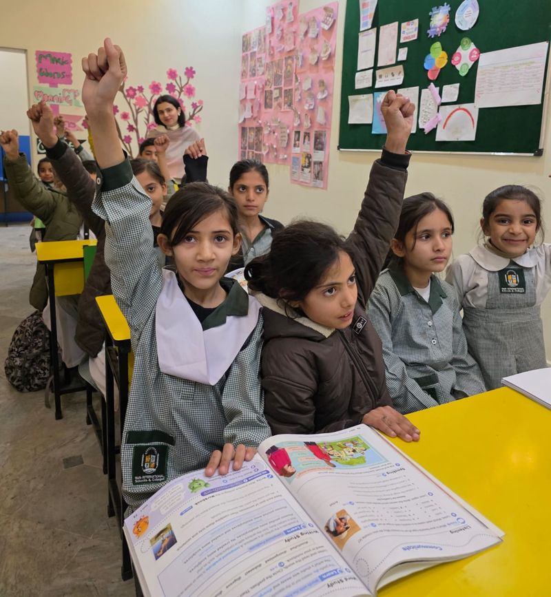 Pupils raising their hands eagerly to answer a question during a lesson
