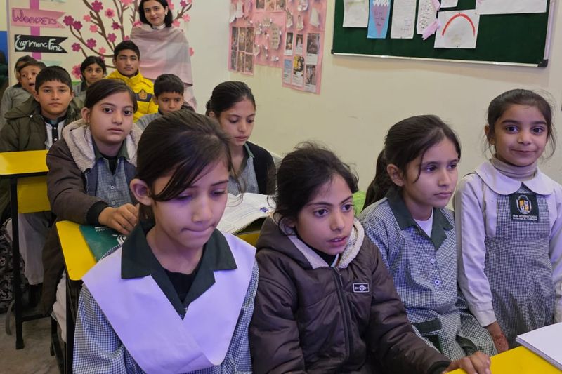 Pupils in RMS uniform sitting at their desks with open books in a bright, decorated classroom