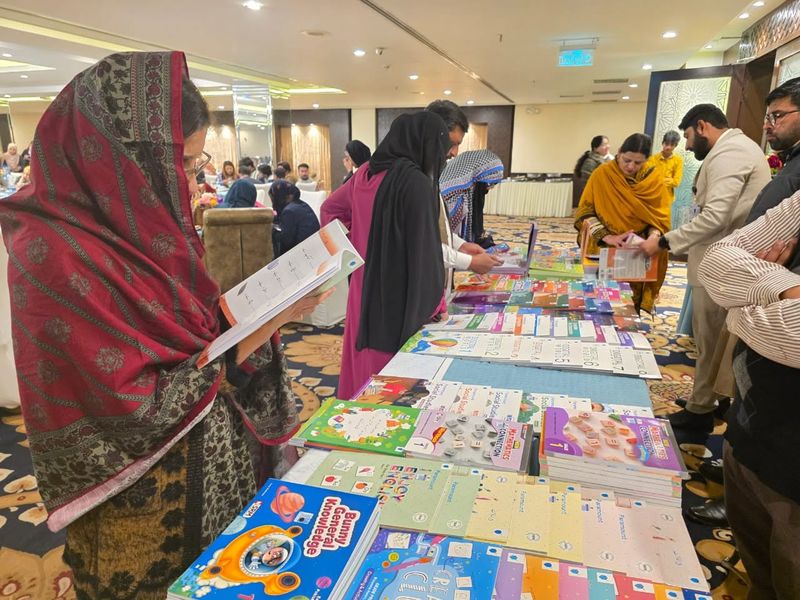 Teachers browsing tables of primary textbooks at a book exhibition