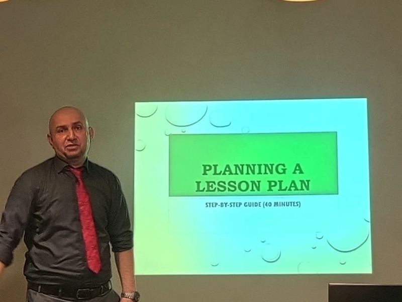 A trainer presenting a session on planning a lesson during a weekly teacher training workshop