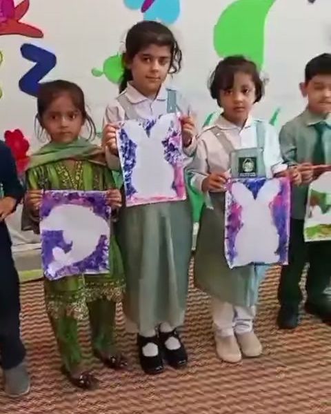 Nursery pupils holding up their painted artwork in a bright classroom