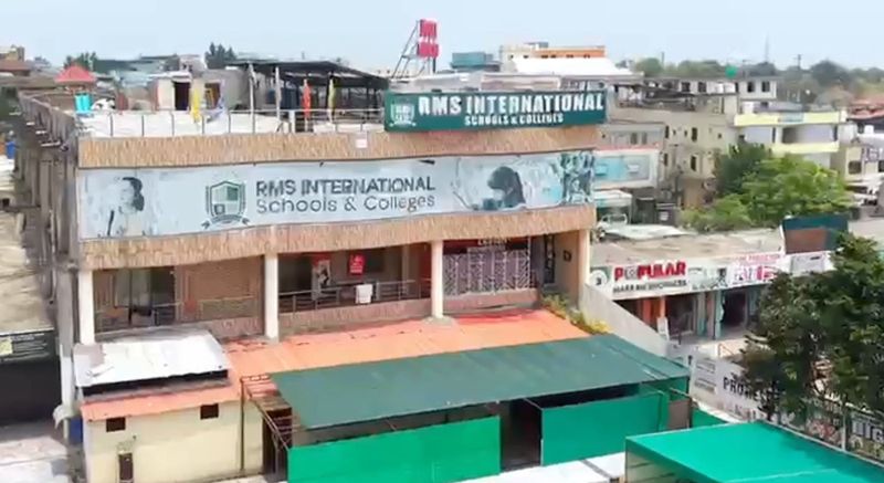 The RMS International Schools and Colleges building with its green rooftop sign and large banner