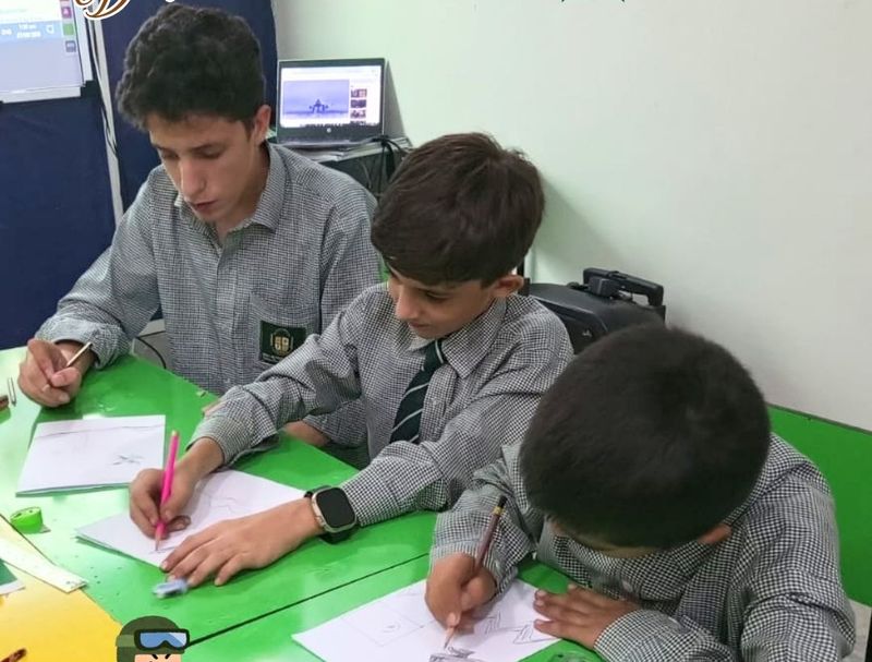 Three boys in school uniform drawing together at a classroom table.