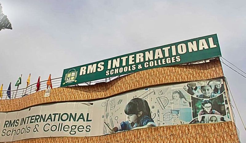 The RMS International Schools & Colleges building with its green rooftop sign and flags.