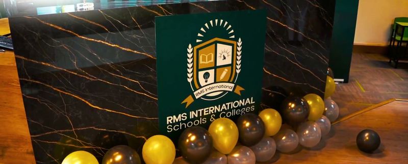 The school reception desk with the RMS crest, decorated with gold and black balloons.