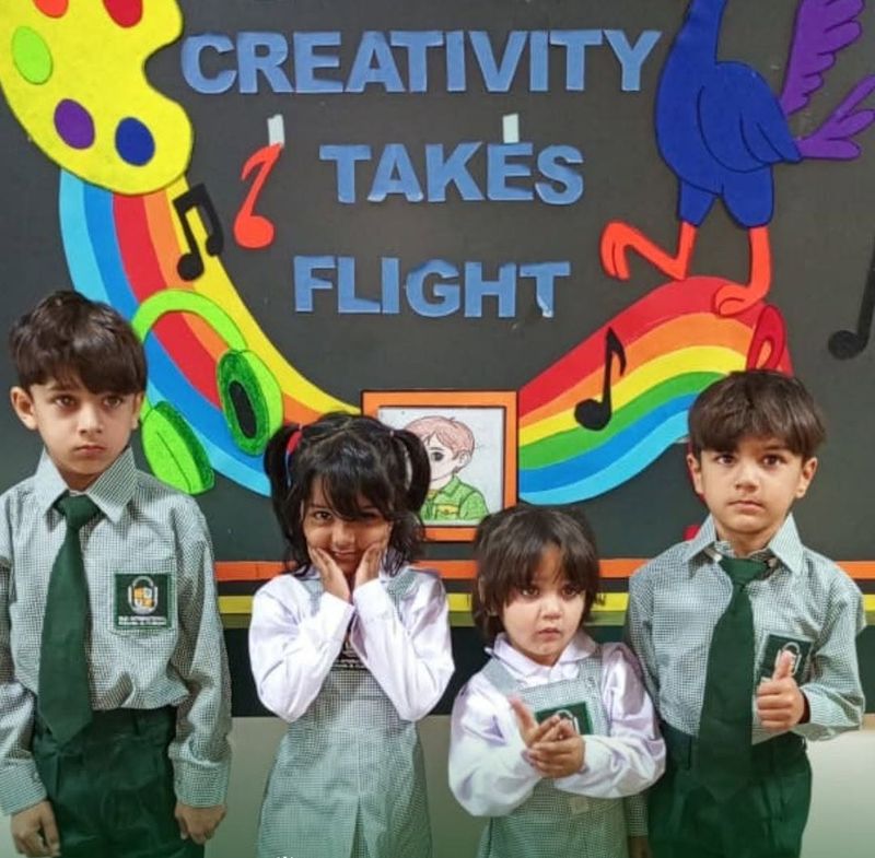 Four pupils in RMS uniform standing in front of a Creativity Takes Flight art display.
