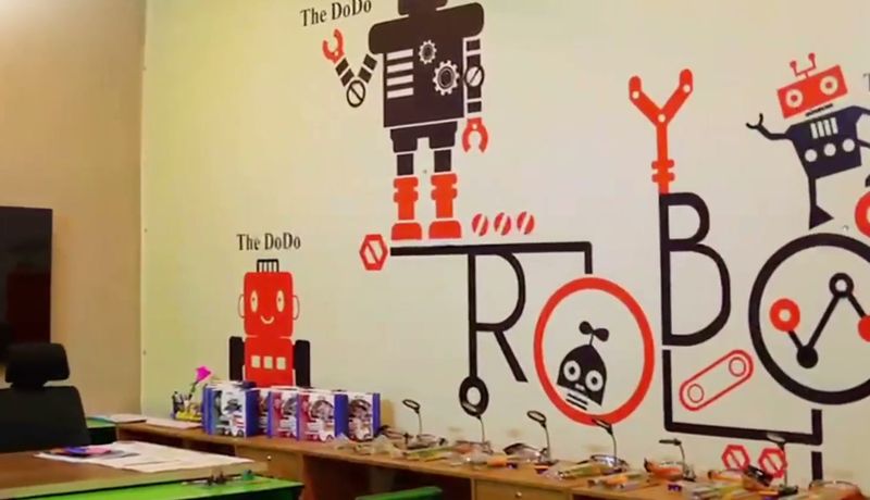 The RMS Robotics and AI lab: a robot mural on the wall, a smart screen and a long workbench laid out with robotics kits.